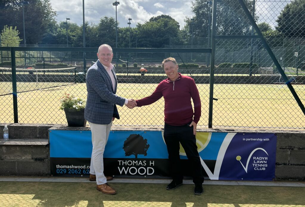 Simon Dews and Cliff Gardner shake hands as they stand in front of Thomas H Wood's banner at Radyr Lawn Tennis Club