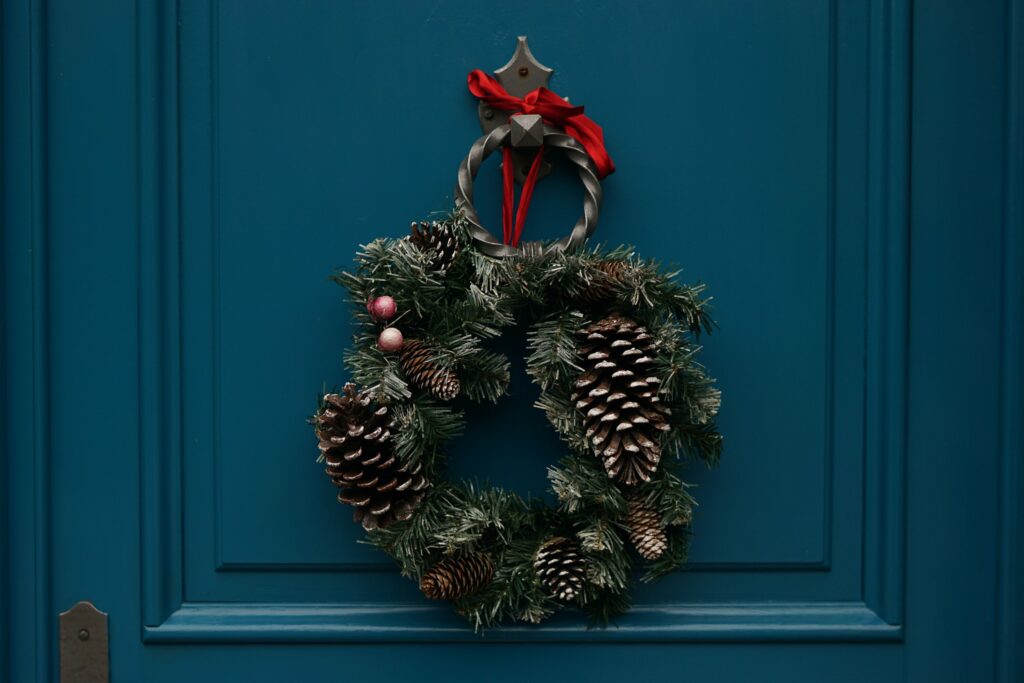 A winter wreath hangs on a blue front door.