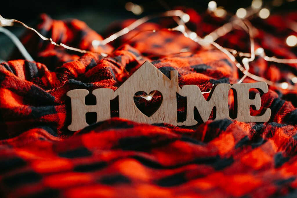 A wooden home sign on an autumnal orange, red and black checked blanket